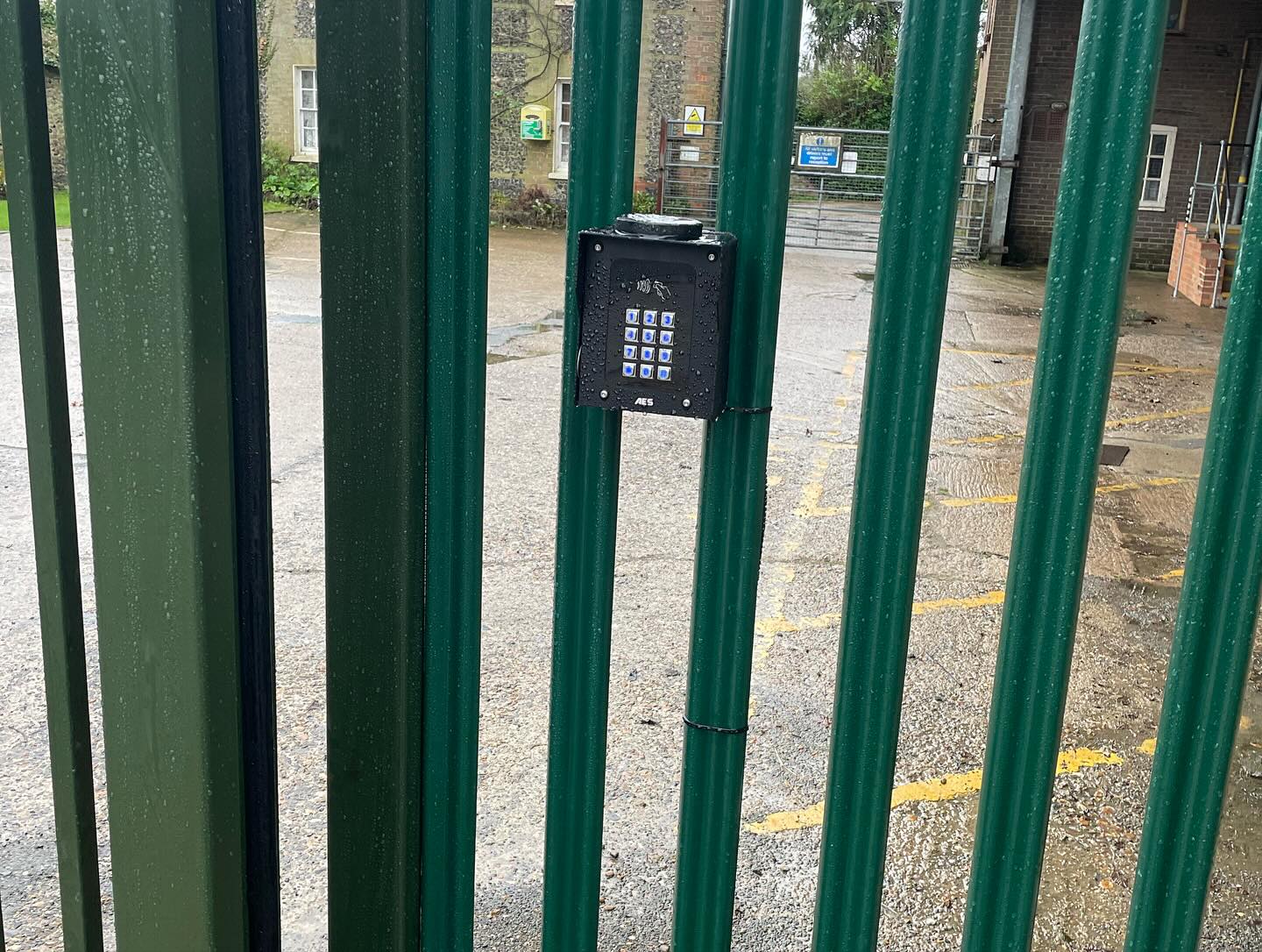 Access control keypad for security gates mounted on green metal railings