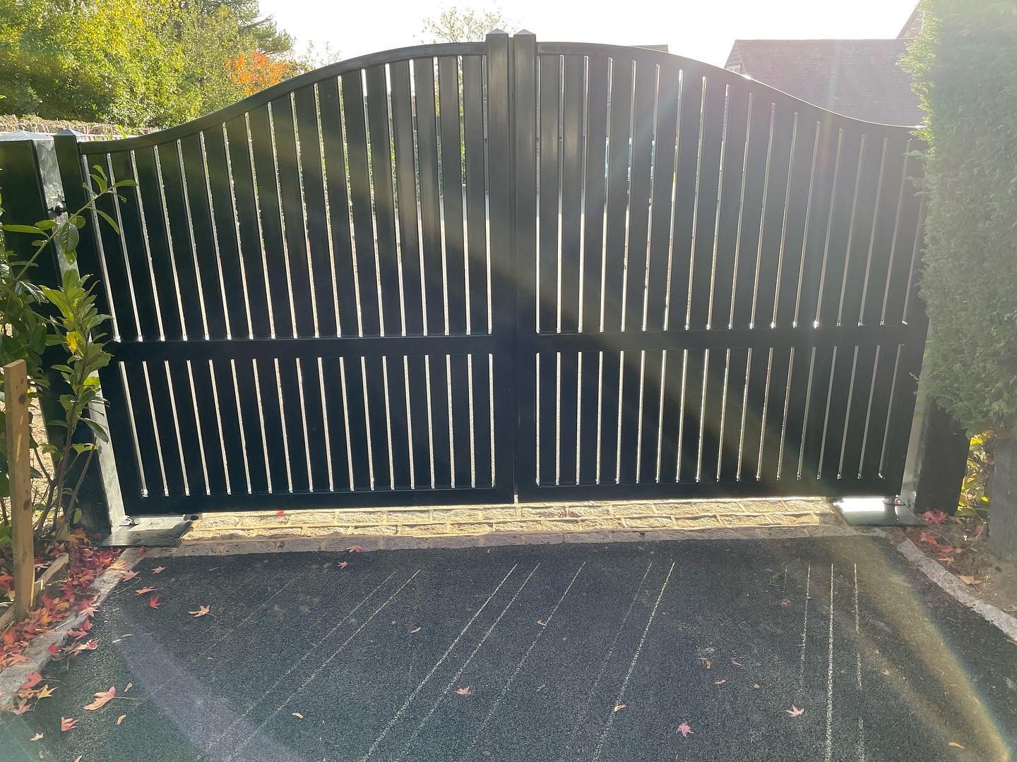 Black arched security gate across a residential driveway