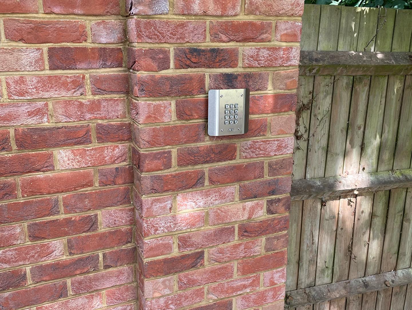 Security gate access keypad mounted on a brick pillar