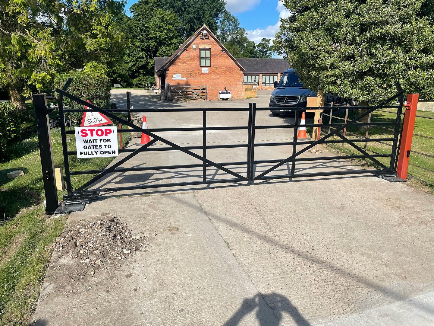 Black metal security gate with access control at a rural entrance