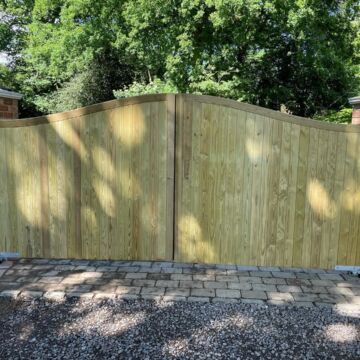 Tall timber security gates between brick entrance pillars