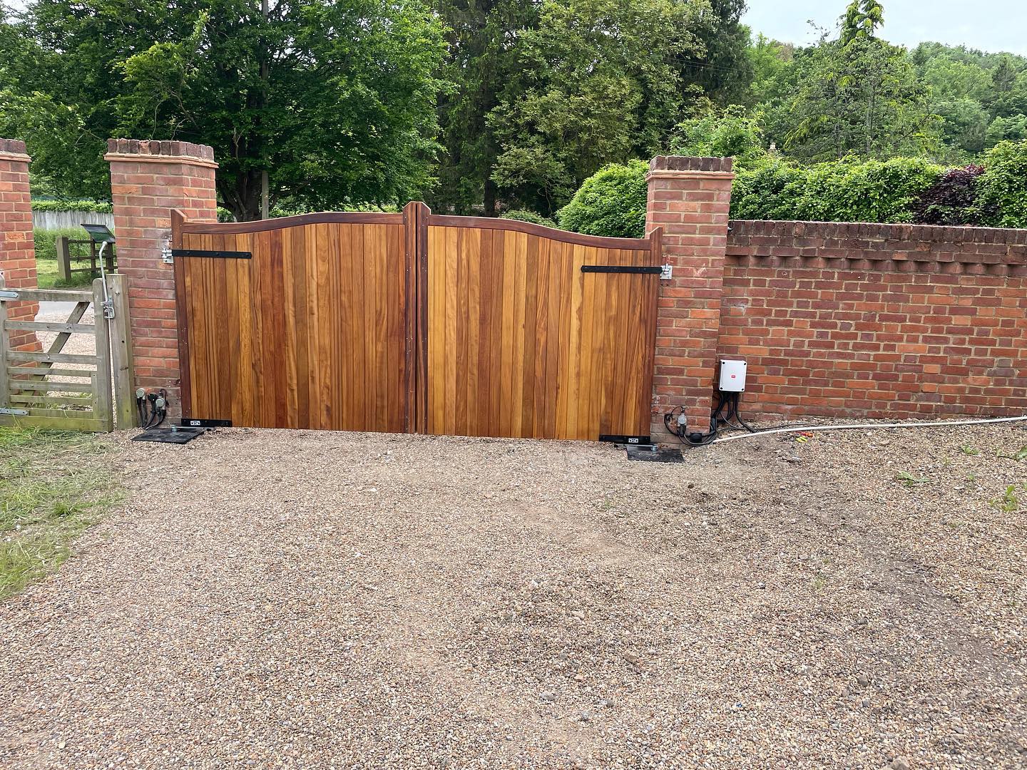 Wooden security gates and automatic openers between brick pillars
