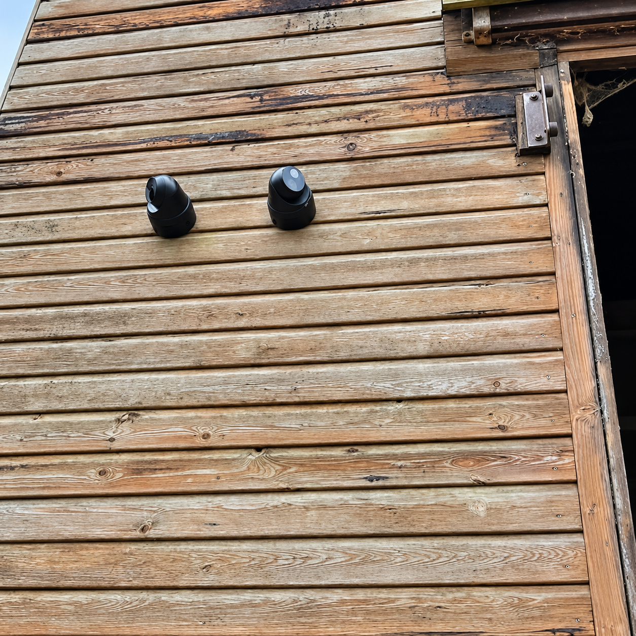 Two outdoor cameras for CCTV systems mounted on timber cladding